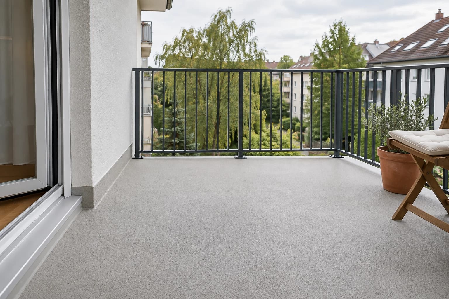 Fertiger Balkon mit heller Bodenfläche, dunklem Metallgeländer und einem Holzstuhl.